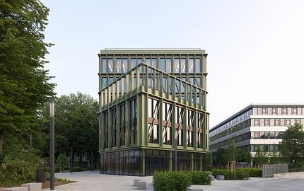 Modern i8-gebouw in München met groene glazen gevels en een begroeid dak, uitgerust met brandbeveiligingsproducten van Wildeboer.